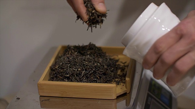 男子双手倒绿茶秤称重商店关闭