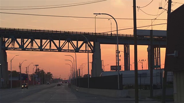 近景:日落时分，在工业城镇繁忙的高速公路上行驶的汽车剪影