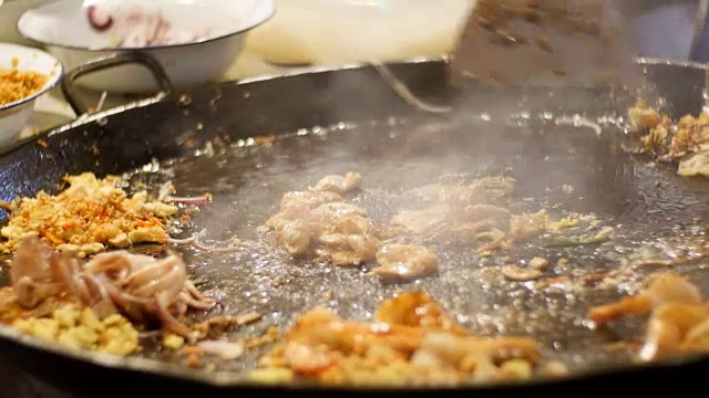 亚洲的街头食品。海鲜，米粉与鸡蛋在一个大煎锅煮。泰国