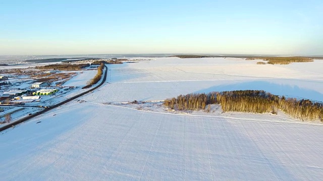 冬天的田野，黎明，橙色的太阳在天空和云彩。无人机拍摄的冬日雪景。无人机拍摄的冬天下雪的乡村。森林中的村庄