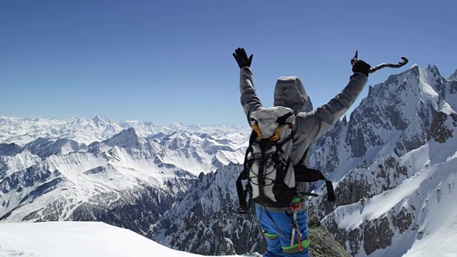 在晴朗的日子里，登山者用冰斧登上了白雪覆盖的山顶。登山滑雪活动。滑雪者冬季在高山户外进行滑雪运动。侧视图。慢动作60p全高清视频