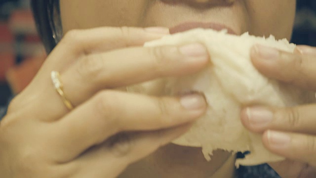 特写:一名亚洲女子正在吃一个馒头