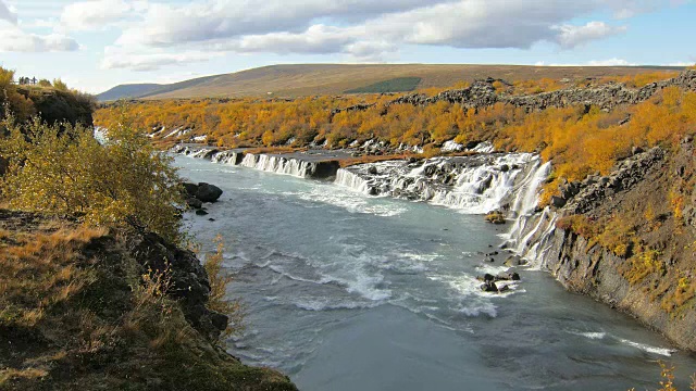 在阳光明媚的秋天，冰岛著名的风景如画的Hraunfossar瀑布峡谷