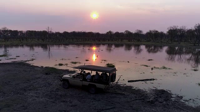在奥卡万戈三角洲，博茨瓦纳，从空中俯瞰一群河马在河里游泳的剪影日落