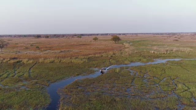 在奥卡万戈三角洲的水道上，一艘游船向照相机驶来的鸟瞰图