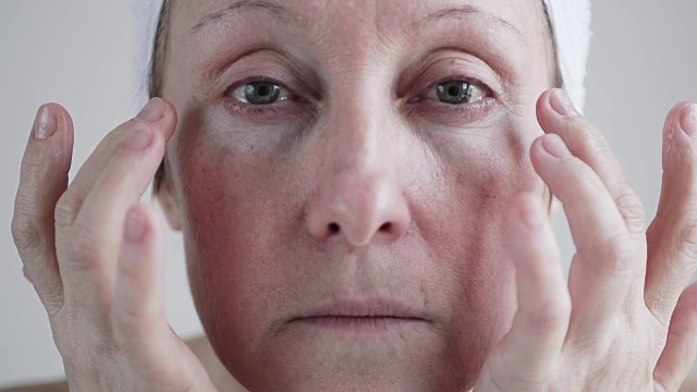 白人中年妇女在脸上涂霜。