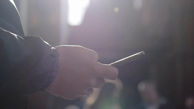 詳情圖-一個男人使用移動智能手機的特寫和陽光與透鏡光暈效果。3840,x2160