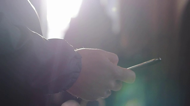 詳情圖-一個男人使用移動智能手機的特寫和陽光與透鏡光暈效果。3840,x2160