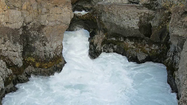 冰岛山区的一条湍急的河流，白天在黑色的悬崖之间奔流