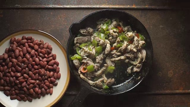 将豆子、辣椒和鸡肉撒在煎锅里。视频
