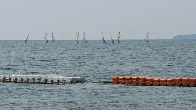 一群冲浪者乘着风帆在海上乘风破浪。泰国芭堤雅