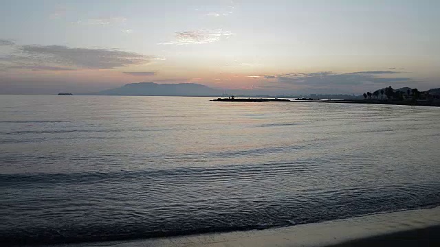 海面风平浪静，黄昏时分，渔民在礁石上捕鱼