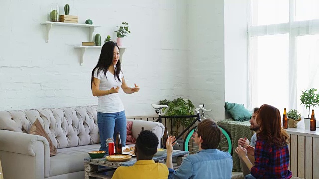 年轻的亚洲女孩玩派对游戏与她的多民族朋友在家里室内