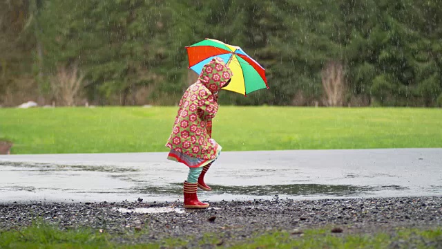 小女孩撑着伞在雨中嬉戏，慢镜头