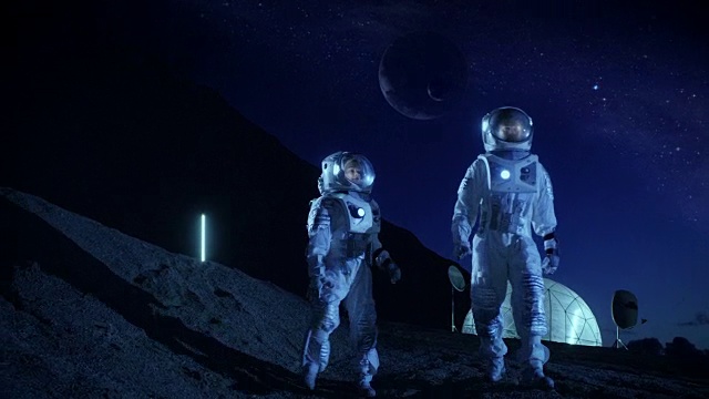 詳情圖-兩名宇航員穿著宇航服探索新發(fā)現(xiàn)的行星。在具有可居住圓頂?shù)谋尘翱臻g基地中，可以看到天空中的外行星。太空殖民的未來概念。