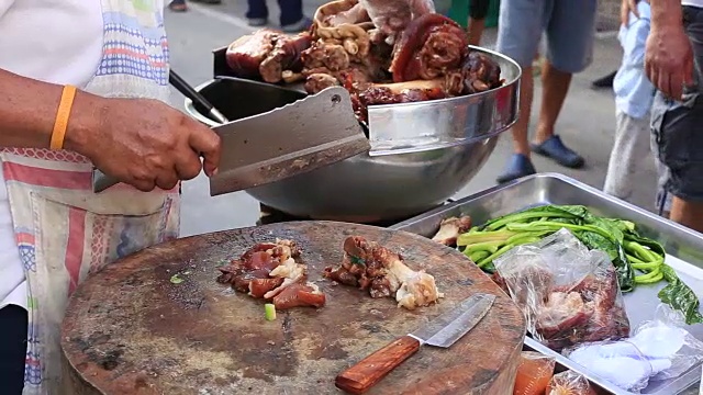 一名泰国男子将熟肉切成薄片，准备在泰国街头食品市场出售。近距离