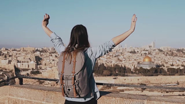 兴奋的欧洲女游客高兴地举起手。以色列耶路撒冷。张开双臂的女人。自由。慢动作
