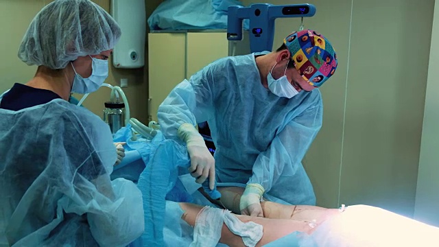 手术室:抽脂手术准备。一组外科医生给一个女孩做抽脂手术。外科医生的工作就像插管。
