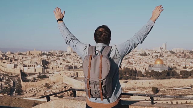 快乐的白人游客男兴奋地举手。以色列耶路撒冷。张开双臂的男人。旅行。慢动作