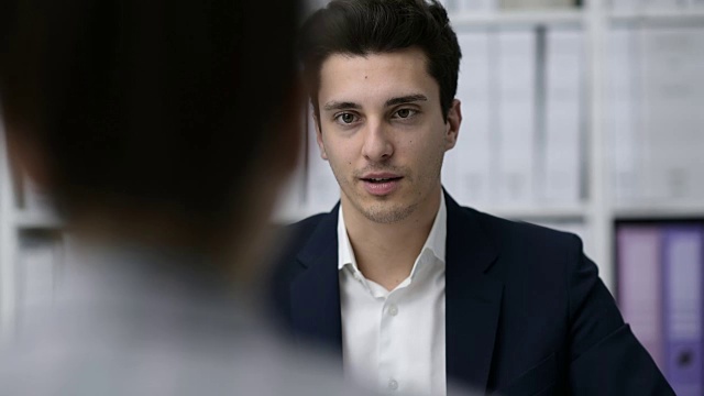 一位业务主管正在办公室开会，他一边说话一边给客户签合同