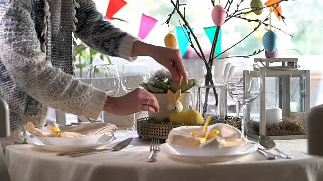 年轻女子用兔子和鸡蛋装饰复活节餐桌