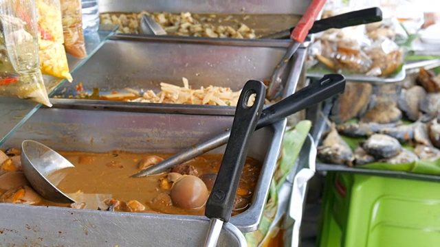 柜台有各种各样的泰国食品。肉、汤、沙拉。亚洲街头食品