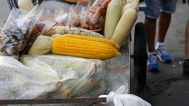 再加上新鲜煮熟的玉米，冒着蒸汽。柜台有各种各样的泰国食品。亚洲街头食品