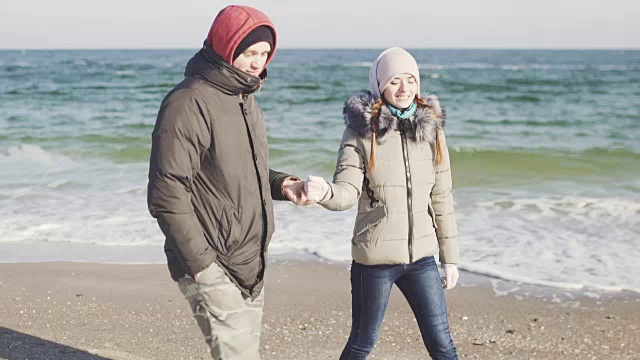 詳情圖-年輕的男人和女人在海灘上散步。在寒冷的冬天，一對(duì)夫婦在海上