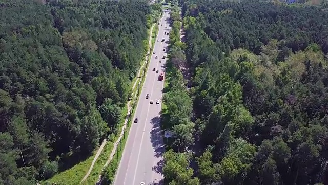 鳥瞰圖的道路在美麗的秋天森林日落。美麗的風景與空曠的鄉(xiāng)村道路，樹木與綠色，紅色和橙色的葉子。高速公路穿過公園。俯視圖從飛行的無人機。夾。鄉(xiāng)間小路