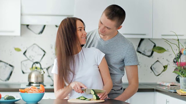 幸福夫妻在轻厨房一起做饭。年轻女子切菜准备健康午餐。