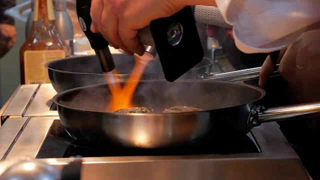用火把燃烧器把火吹进肉排里。