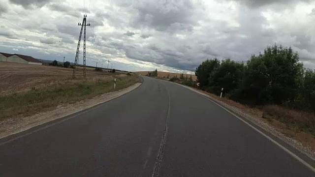 一个骑摩托车的人在雨天沿着沙漠中的道路行驶。第一人称视角