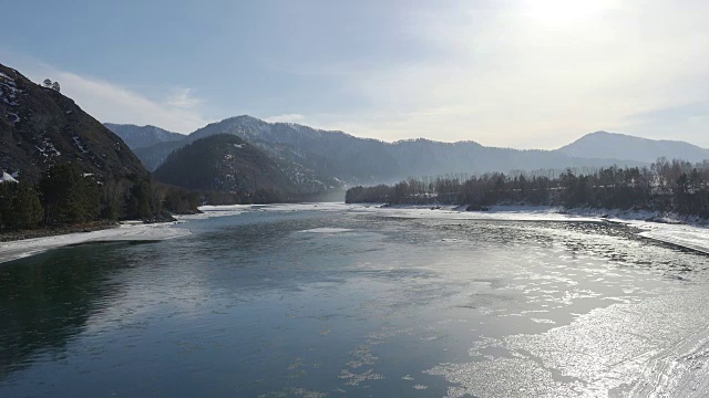 冬季鸟瞰阿尔泰河卡顿，背景为水中浮冰和群山
