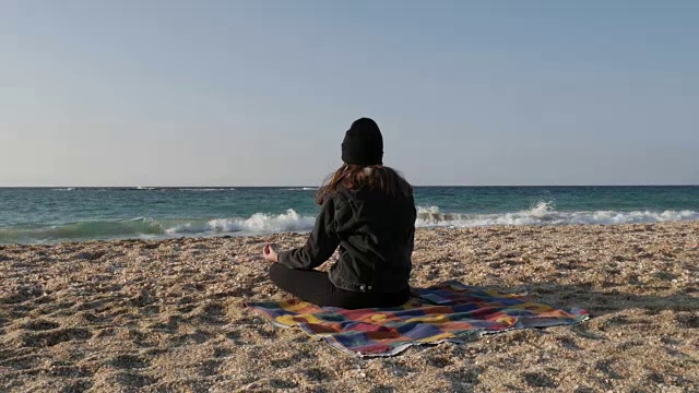 一个凉爽的秋日，一个女孩在地中海岸边沉思。