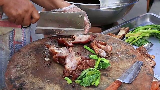 一名泰国男子将熟肉切成薄片，准备在泰国街头食品市场出售。近距离