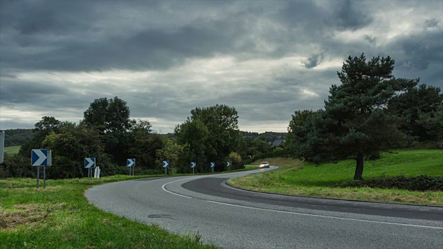 时间流逝，汽车行驶在沥青弯曲的道路上，穿过绿色的田野和森林。