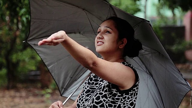 女人撑着伞，享受着大雨。