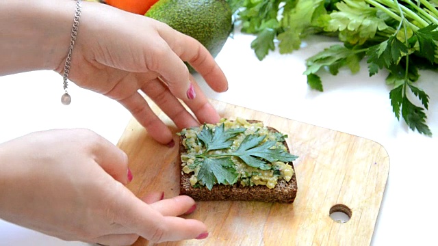 用刀抹在牛油果面包上。生的和健康的素食食品