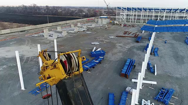 一个大型建筑起重机，人们在一个现代化工厂的建筑工地工作。起重机组装金属框架