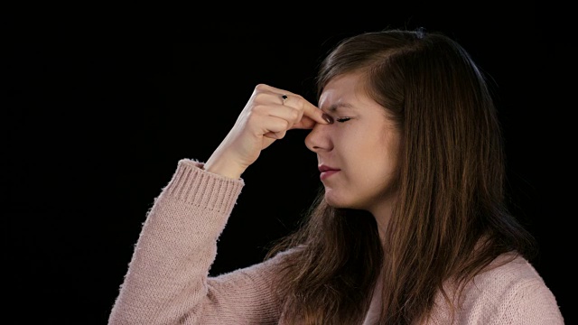 一位头疼的年轻女士在按摩鼻梁