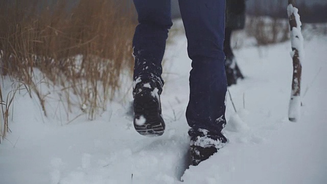 一个男人和一个女人在雪地上走过。卡压在雪堆上。稳定的拍摄