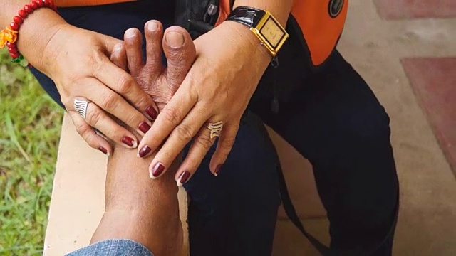 成熟的女人按摩一个老人的脚特写
