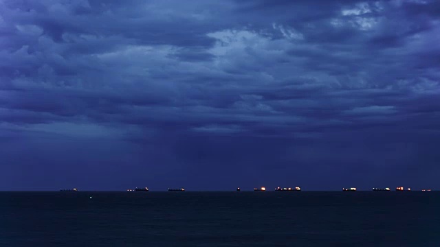 间隔拍摄。夜幕降临，海面上乌云密布，船在远方