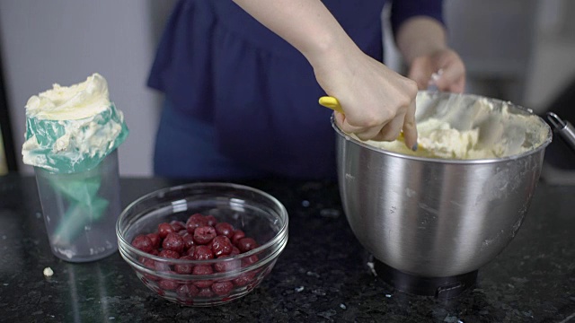 一位女士正在用罐装浆果制作奶油作为甜点