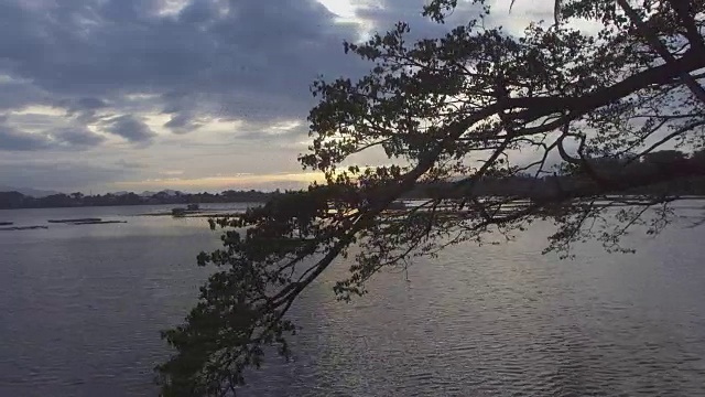 夕阳穿过树枝越过竹制的建筑在湖中央。剪影,无人机空中