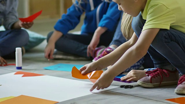 幼儿在老师的帮助下做纸工艺品