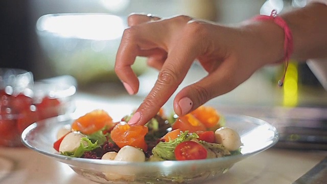 烹饪女士装饰地中海菜鲑鱼片上面，健康的午餐