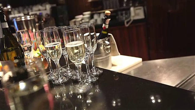 自助餐桌上放着一杯香槟和葡萄酒，桶里装着一瓶香槟或葡萄酒，背景是人们在跳舞，模糊的剪影