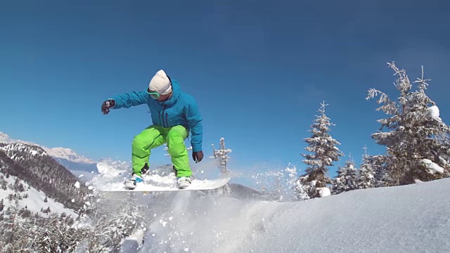 慢动作:专业滑雪板运动员骑着雪橇下坡，然后跳到空中。