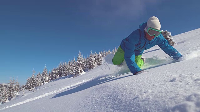 特写:专业滑雪板在风景优美的骑下山的山落入新鲜的雪